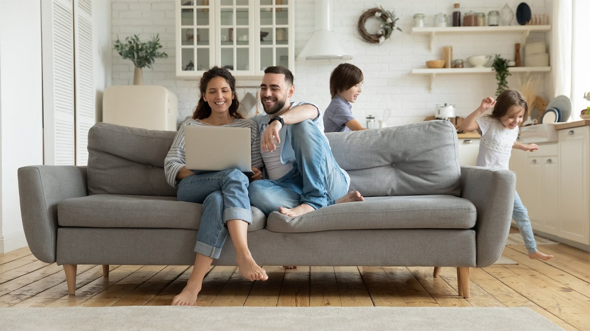 Couple sitting on the couch in a living room researching heat pump benefits